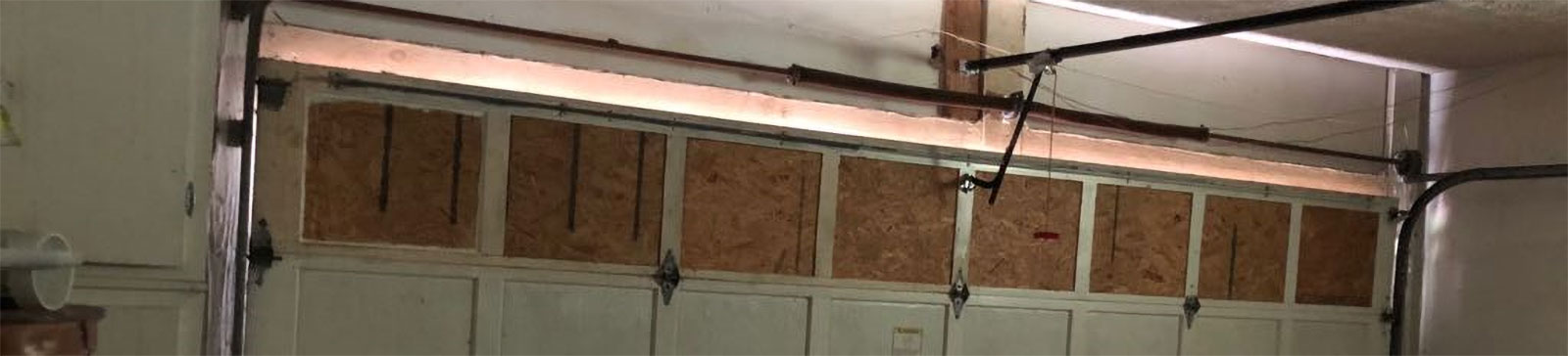Close-up of a bent and dented lower garage door panel before replacement in Winter Garden, FL.